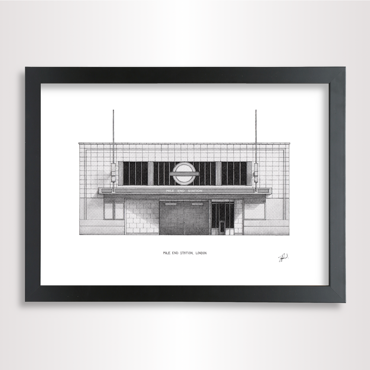 A framed black and white architectural art print of the Mile End Tube station in London, featuring a detailed illustration of the building facade inside a black frame.