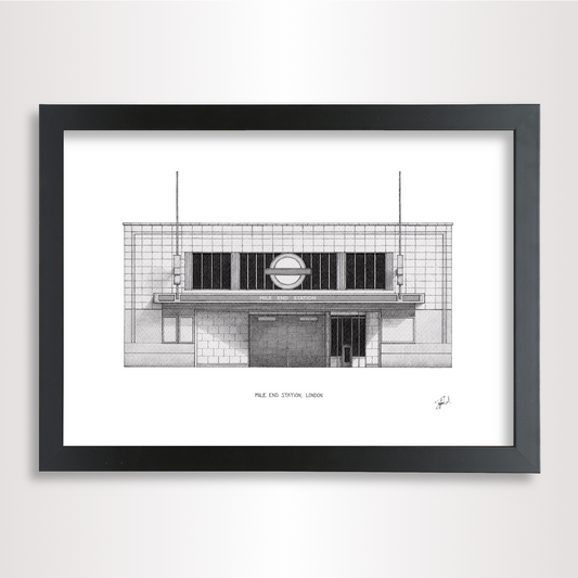 A framed black and white architectural art print of the Mile End Tube station in London, featuring a detailed illustration of the building facade inside a black frame.